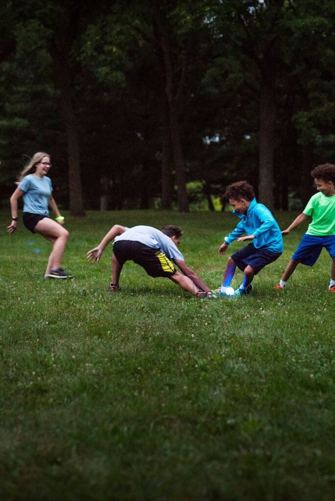 Kids enjoying a glowing soccer game in the park at dusk, showcasing active outdoor fun.
