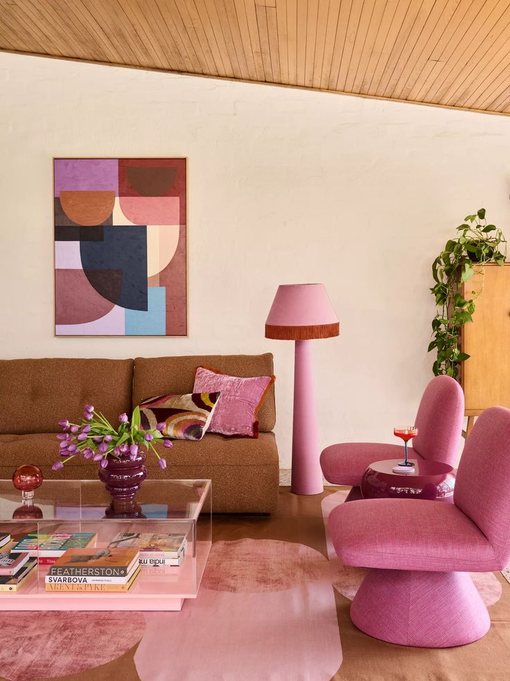 Stylish living room with brown sofa, pink accents, abstract art, tulip vase, and cozy modern decor.