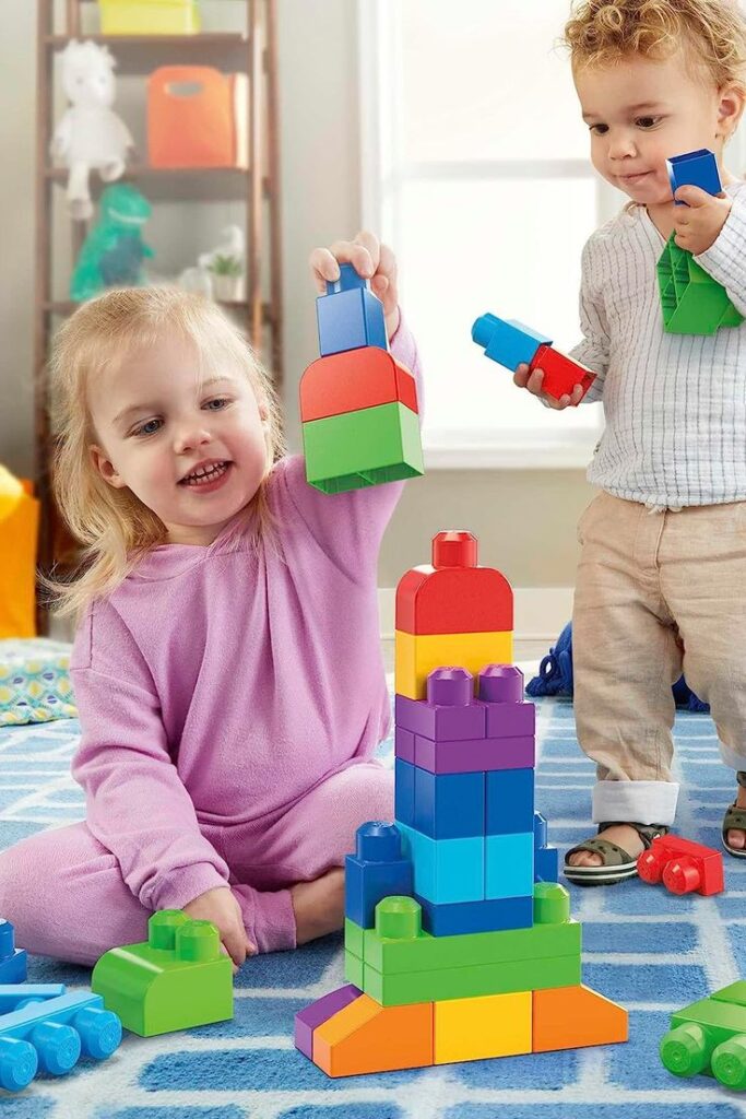 Children playing with colorful building blocks on a blue rug in a bright room.