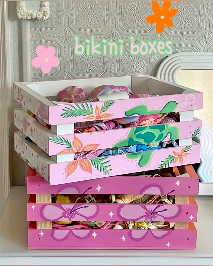 Colorful painted crates labeled bikini boxes filled with vibrant bikinis, perfect for organizing summer swimwear.