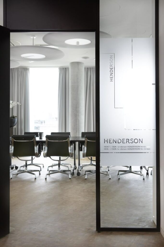 Sleek modern conference room with glass door and ergonomic chairs, curtain-covered windows in a professional office setting.