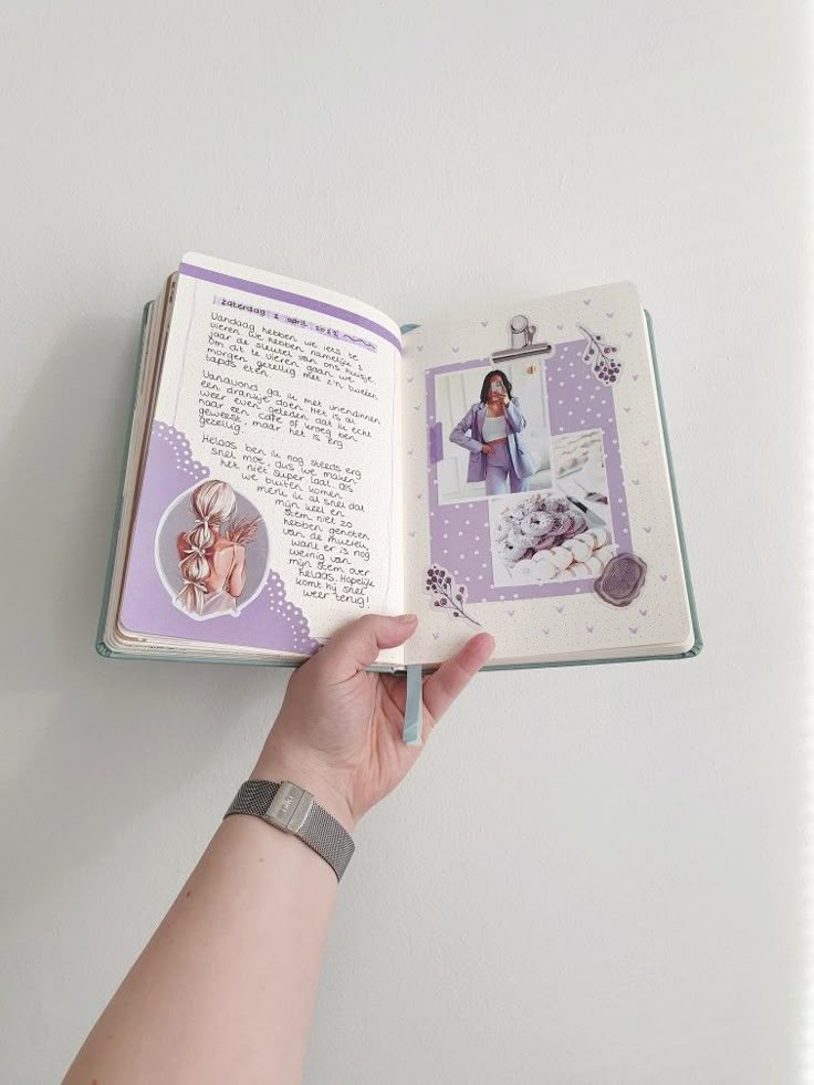 Open journal with handwritten notes and collage on a lavender-themed page, held against a white background.
