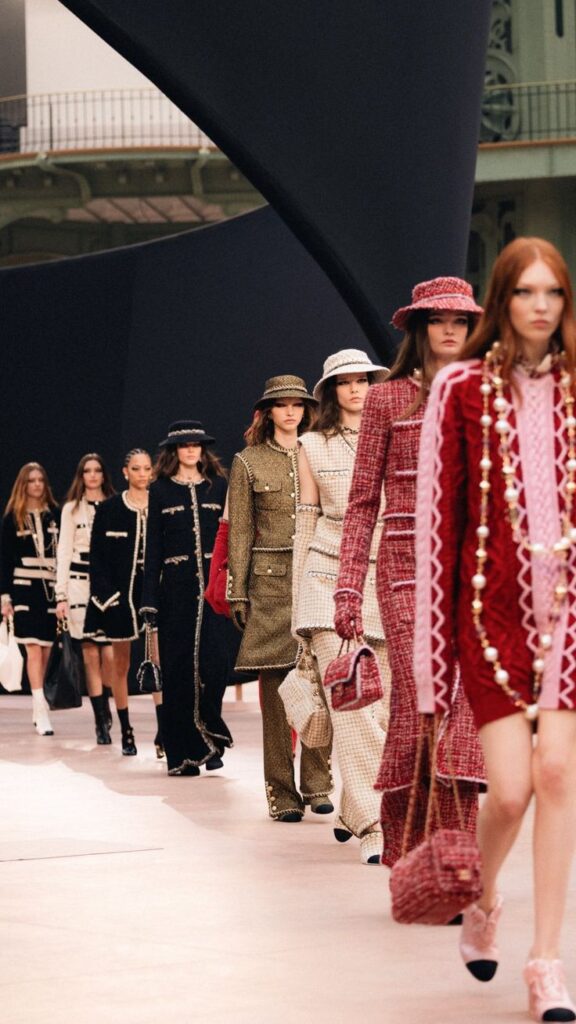 Fashion runway show featuring models in chic tweed ensembles, showcasing a blend of classic and modern styles.