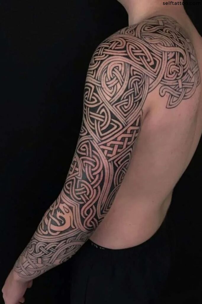 Intricate black Celtic knotwork tattoo sleeve on a person's arm and shoulder, showcasing detailed pattern artistry.