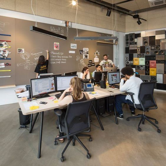 Modern coworking space with young professionals at computers and a creative chalkboard wall.