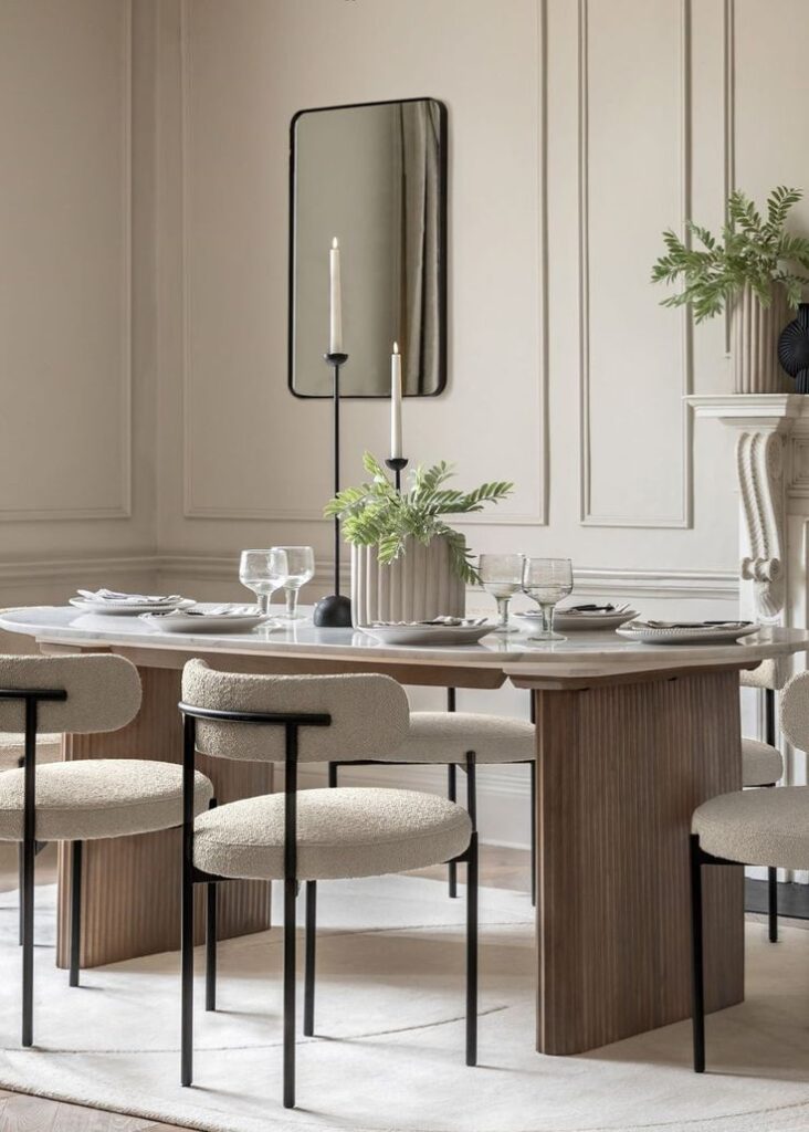 Charlie Marble 8 Seater Dining Table Modern dining room with elegant table, beige chairs, tall candles, mirror, and green plant centerpiece. | Sky Rye Design Modern dining room with elegant table, beige chairs, tall candles, mirror, and green plant centerpiece.