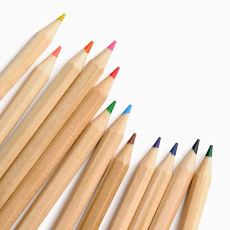 Assorted colored pencils arranged in a row on a white background, showcasing various vibrant tips.