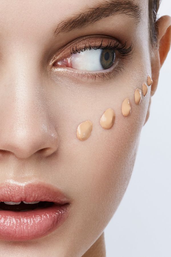Close-up of a woman's face with foundation applied on cheek, illustrating makeup application technique.