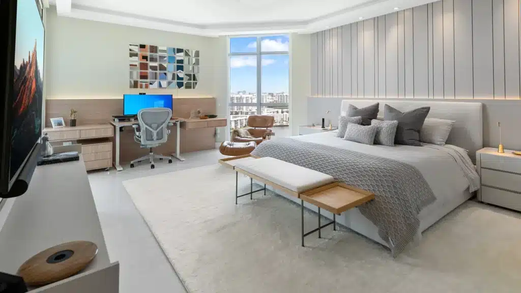 Modern bedroom with office desk, sleek decor, and city view from large window. Cozy bed and stylish workspace combined.