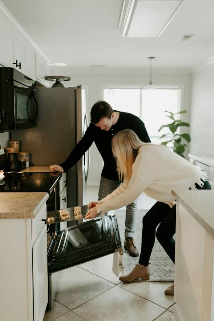 Couple baking cookies together in a cozy kitchen, enjoying a home-cooked moment.