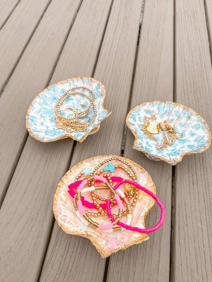 Decorative shell-shaped dishes displaying colorful bracelets on a wooden surface.