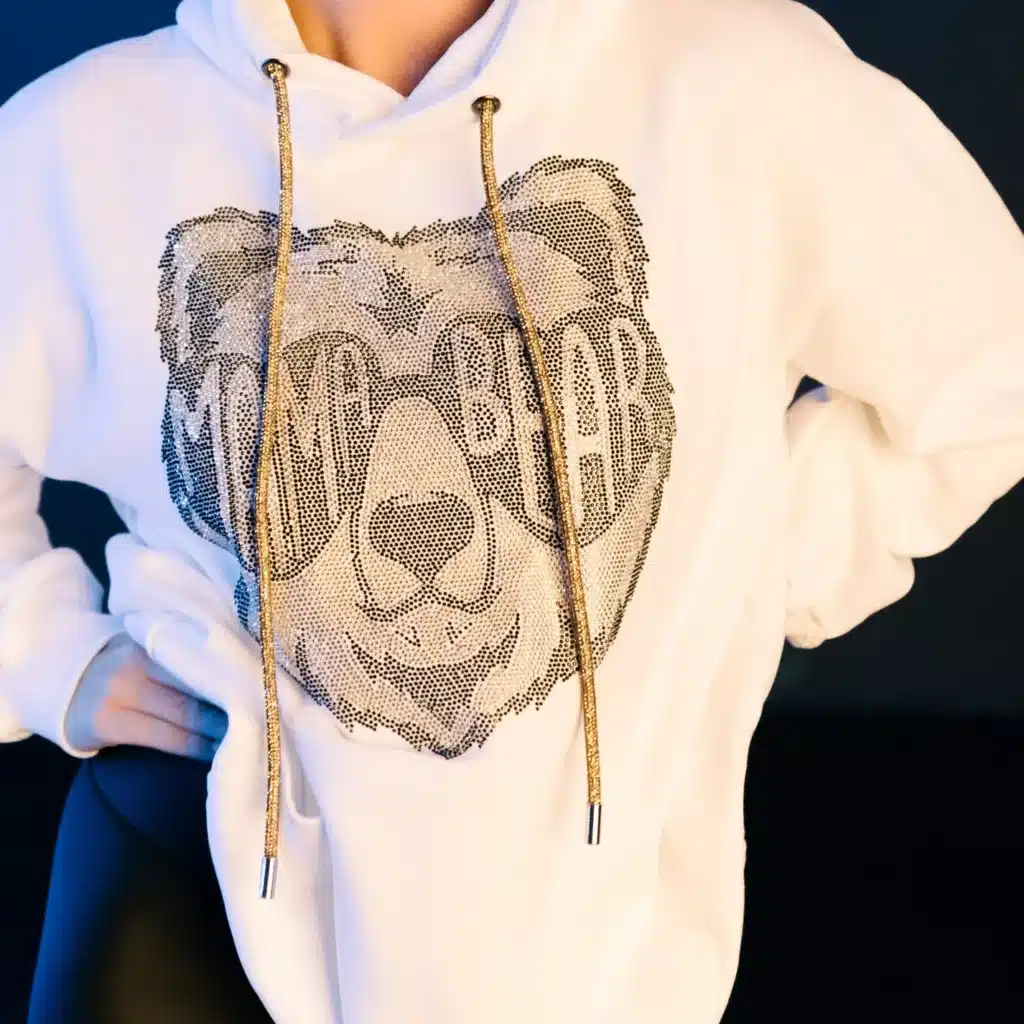 White hoodie with Mama Bear rhinestone design, gold drawstrings.