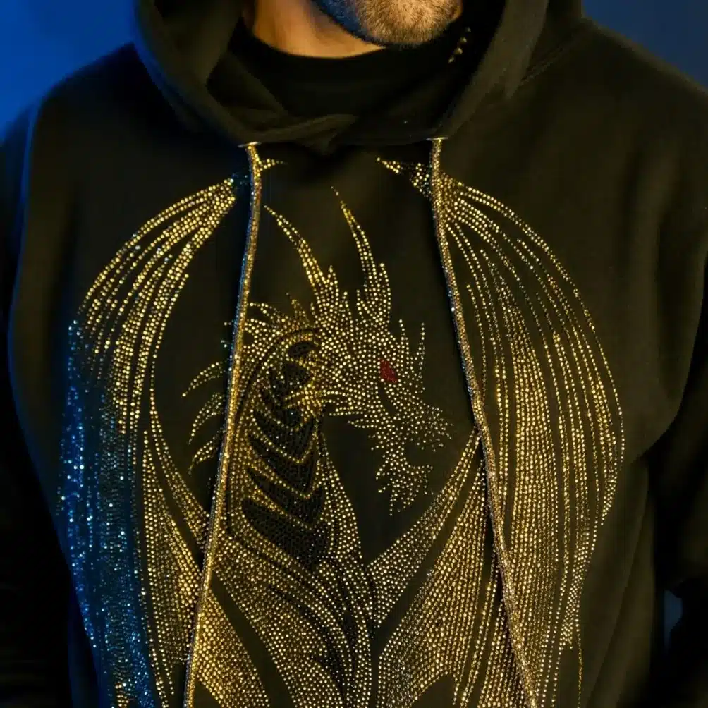 Man in a black hoodie with a gold dragon design, set against a blue background.