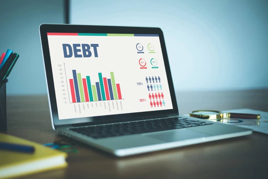 Laptop displaying debt analysis charts and graphs on screen.