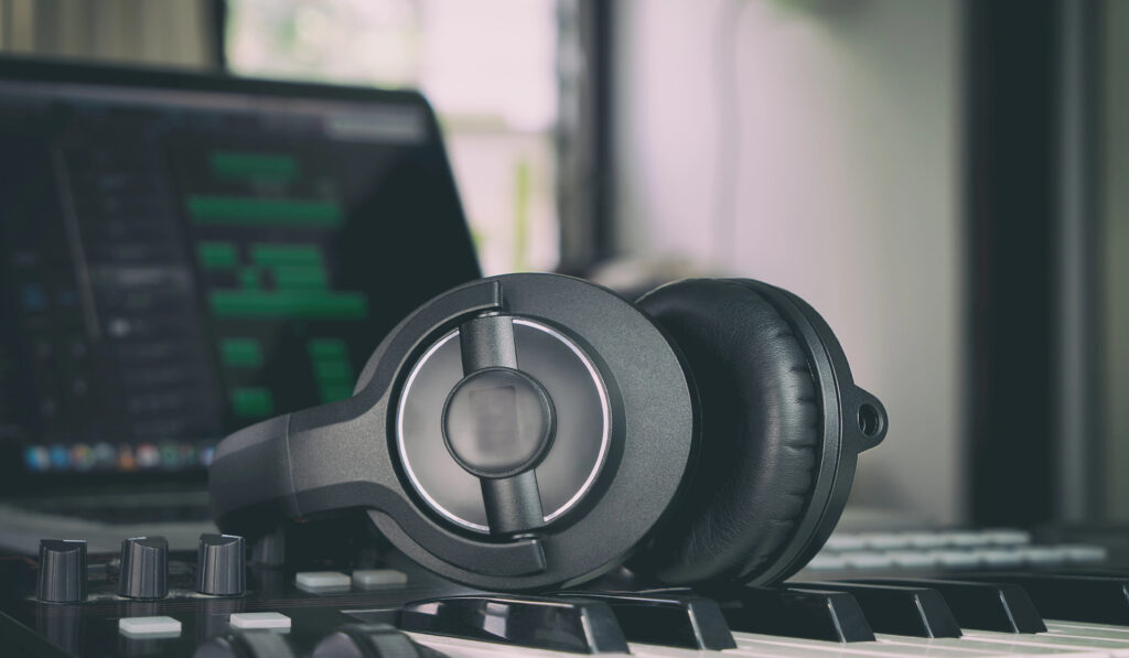 Depositphotos_145484951_XL Black headphones on a keyboard with a laptop background, ideal for music production. | Sky Rye Design Black headphones on a keyboard with a laptop background, ideal for music production.