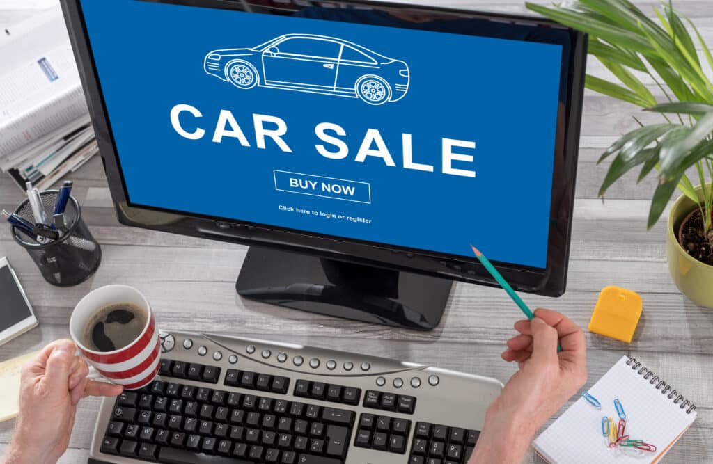 Car sale concept on a computer Computer screen displaying online car sale with Buy Now button, surrounded by office supplies and coffee cup. | Sky Rye Design Computer screen displaying online car sale with Buy Now button, surrounded by office supplies and coffee cup.