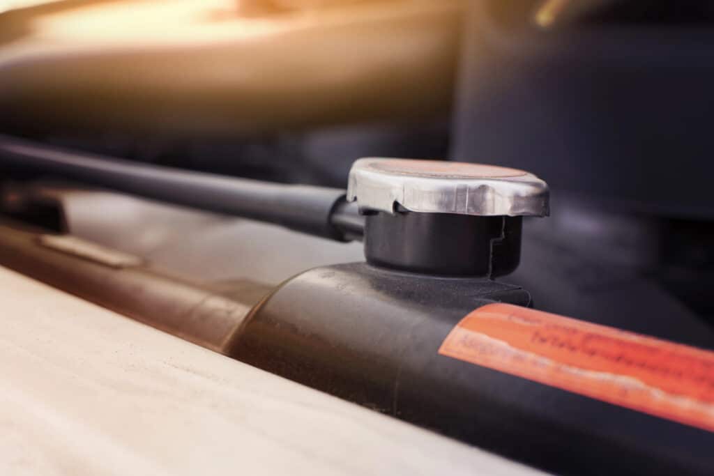 Close-up of a car radiator cap on an engine, illustrating vehicle maintenance details.