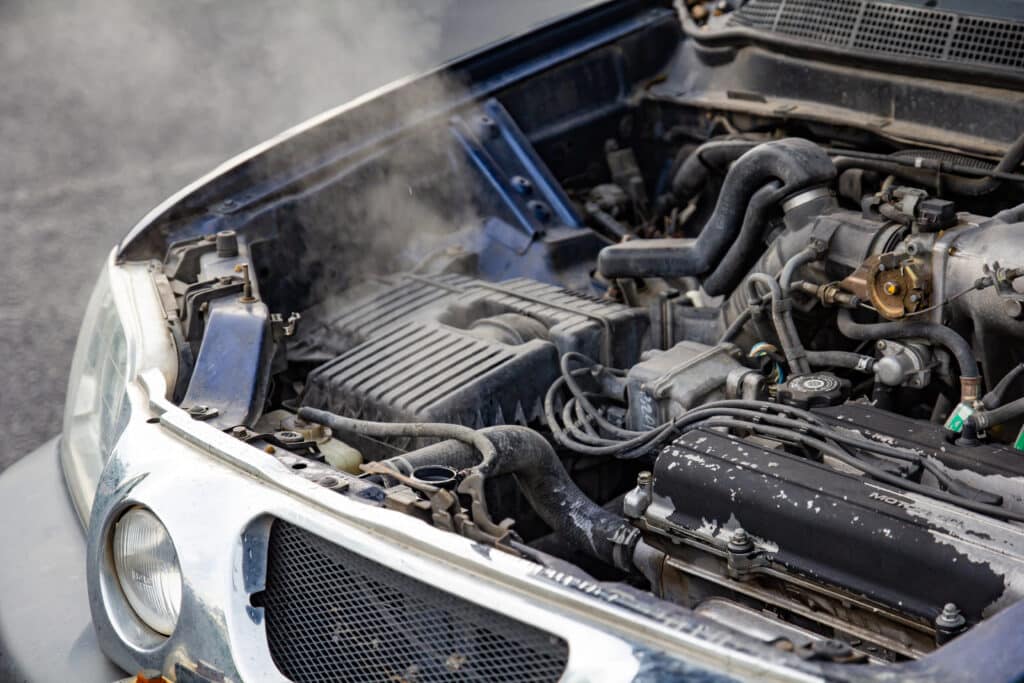 Car engine overheating, emitting steam with hood open, showing engine parts and potential mechanical issues.