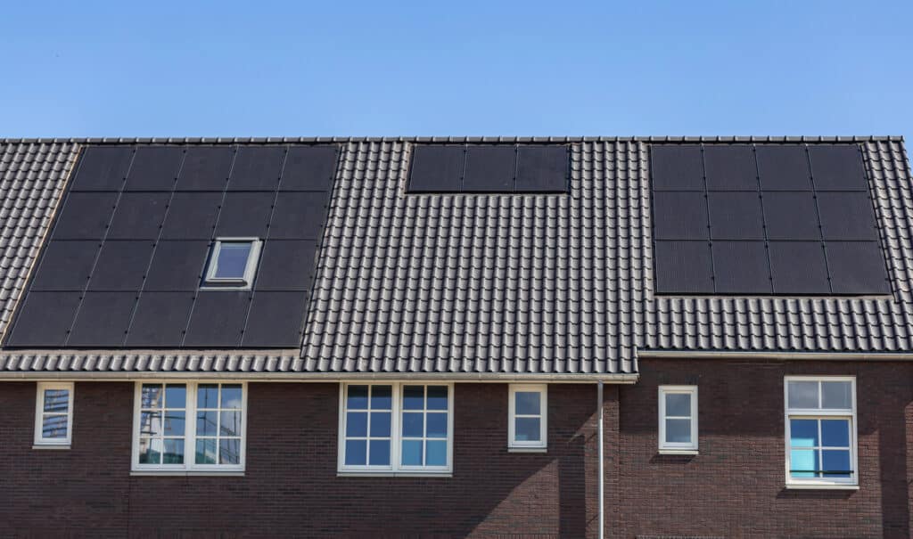 Roof with installed solar panels under clear sky, enhancing green energy efficiency on modern brick home.