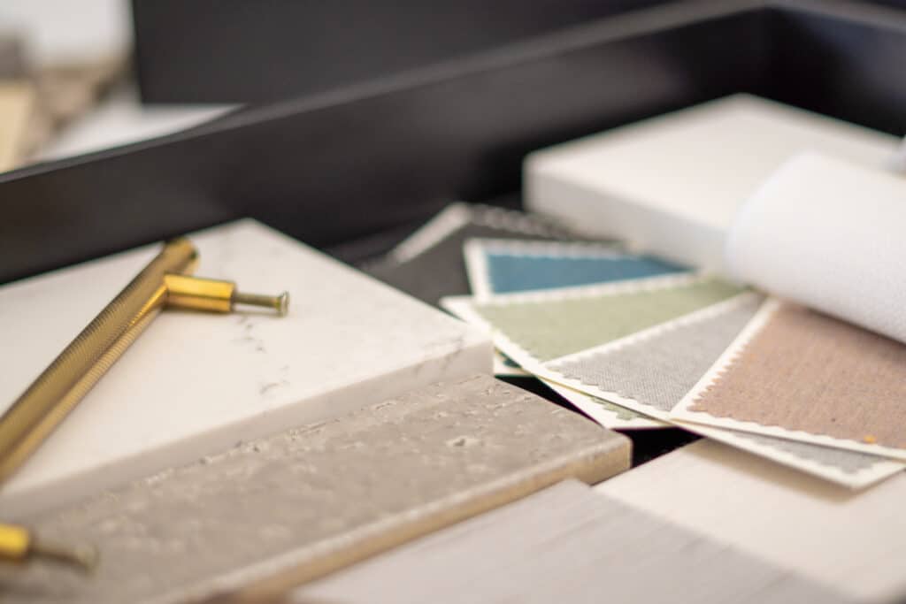 Interior designers working table an architectural plan of the house a color palette Interior design materials and tools, including fabric swatches, marble tiles, and brass handles displayed on a table. | Sky Rye Design Interior design materials and tools, including fabric swatches, marble tiles, and brass handles displayed on a table.