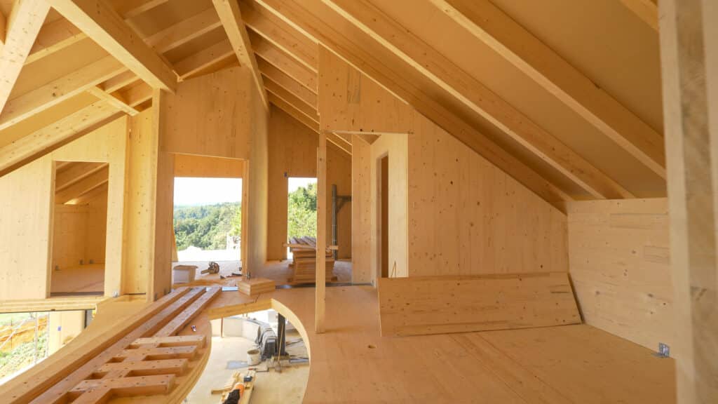 Depositphotos_489918828_XL Wooden house under construction with exposed timber framing and open windows, showcasing natural light and craftsmanship. | Sky Rye Design Wooden house under construction with exposed timber framing and open windows, showcasing natural light and craftsmanship.