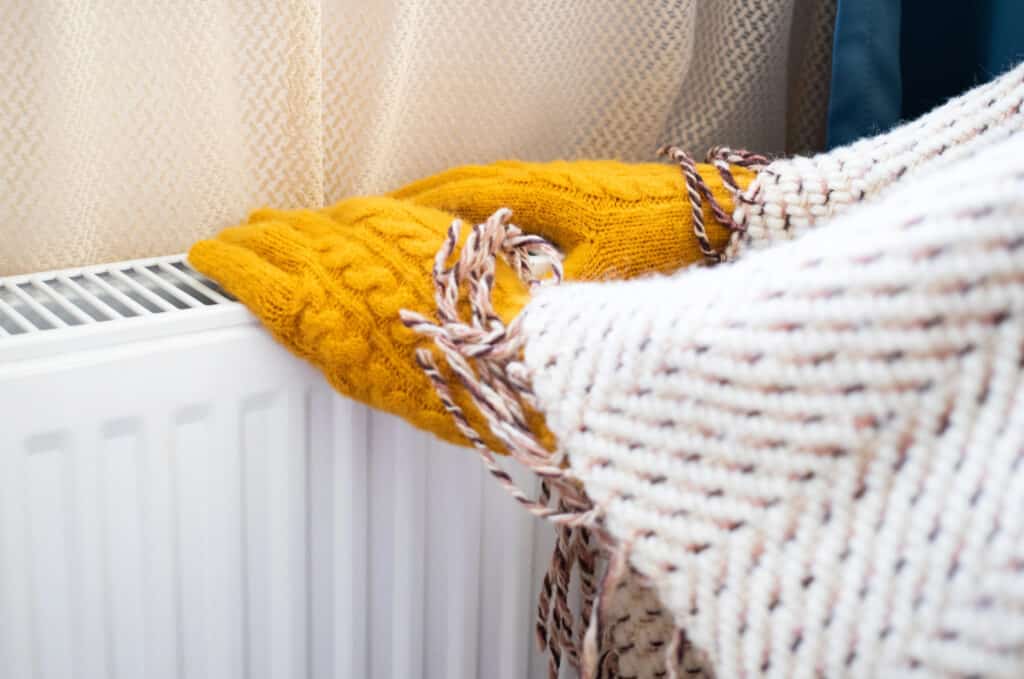 Cozy knitted socks and blanket on a radiator, keeping warm indoors during winter.