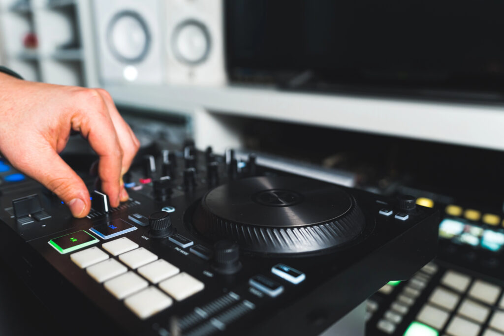Hand adjusting DJ controller knobs in a music studio for mixing beats.