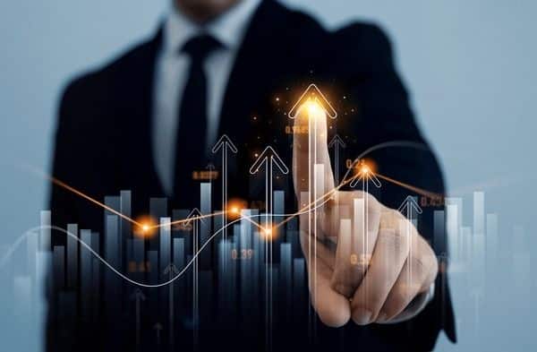 Businessman pointing at rising graph arrows, symbolizing growth and success in business strategy and innovation.