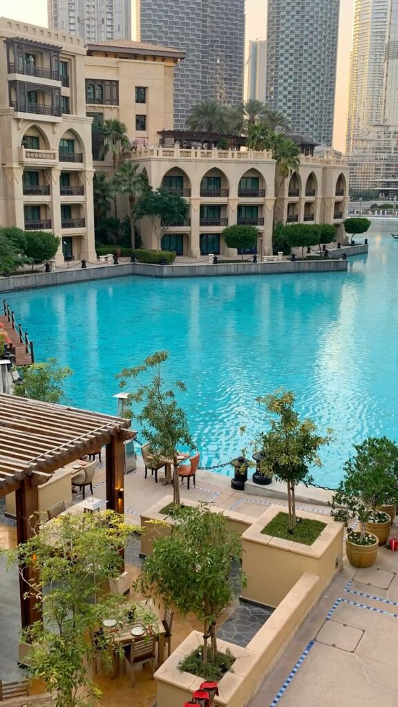 Luxurious hotel pool with palm trees, surrounded by stunning architecture and cityscape in the background.