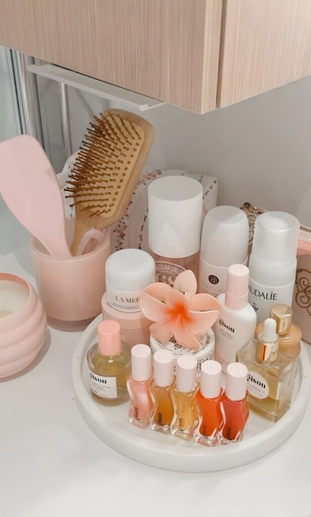 Elegant vanity setup with skincare products, nail polish, and a pink flower accent for a chic beauty routine.