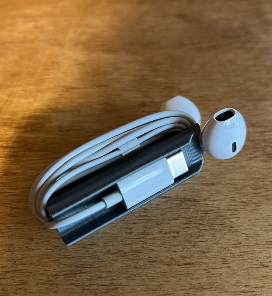 White earphones neatly wrapped around a small case on a wooden surface.