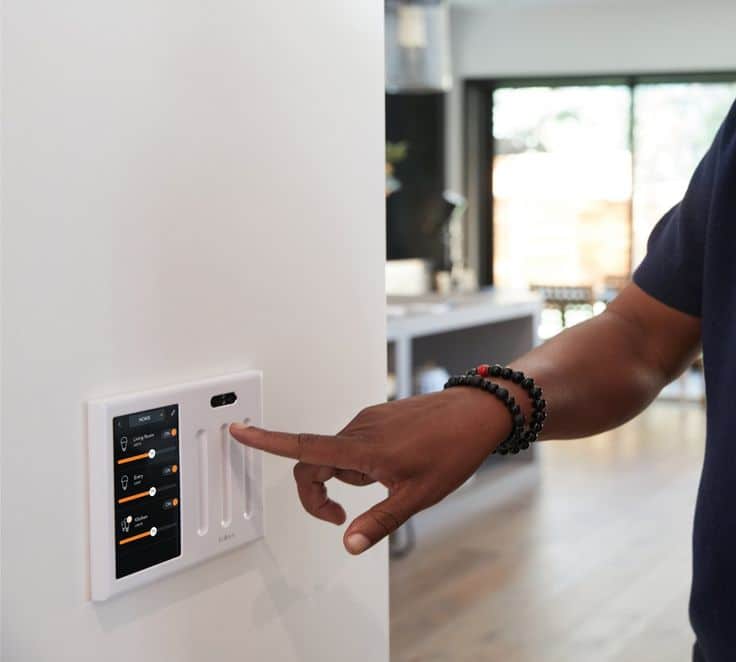 Person using smart home touchscreen to adjust lighting settings.
