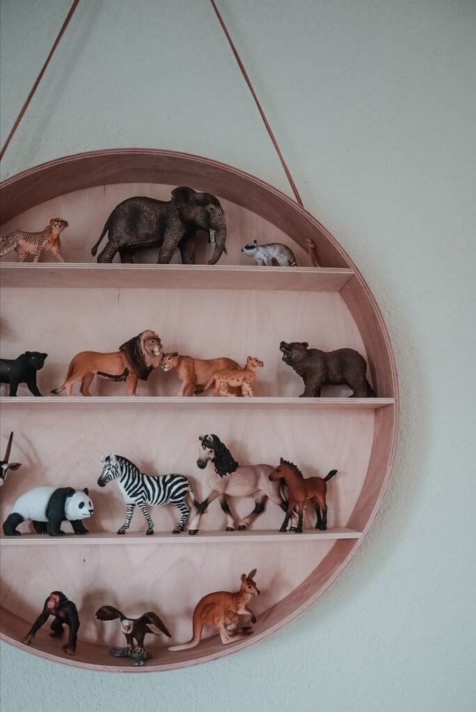Round wall shelf with assorted animal figurines, including an elephant, lion, zebra, and panda, for decorative display.