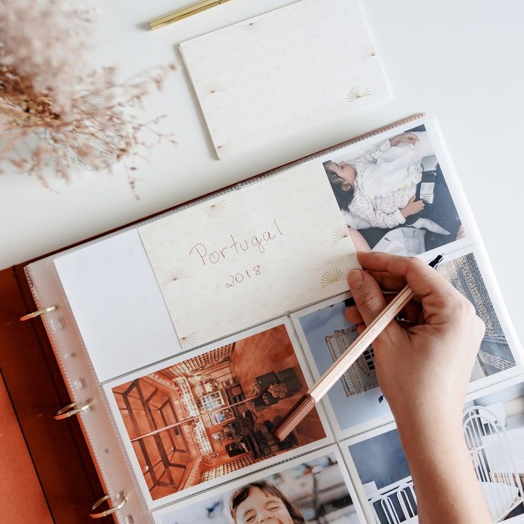 Photo album labeled Portugal 2018 with hand arranging photos on a white table.