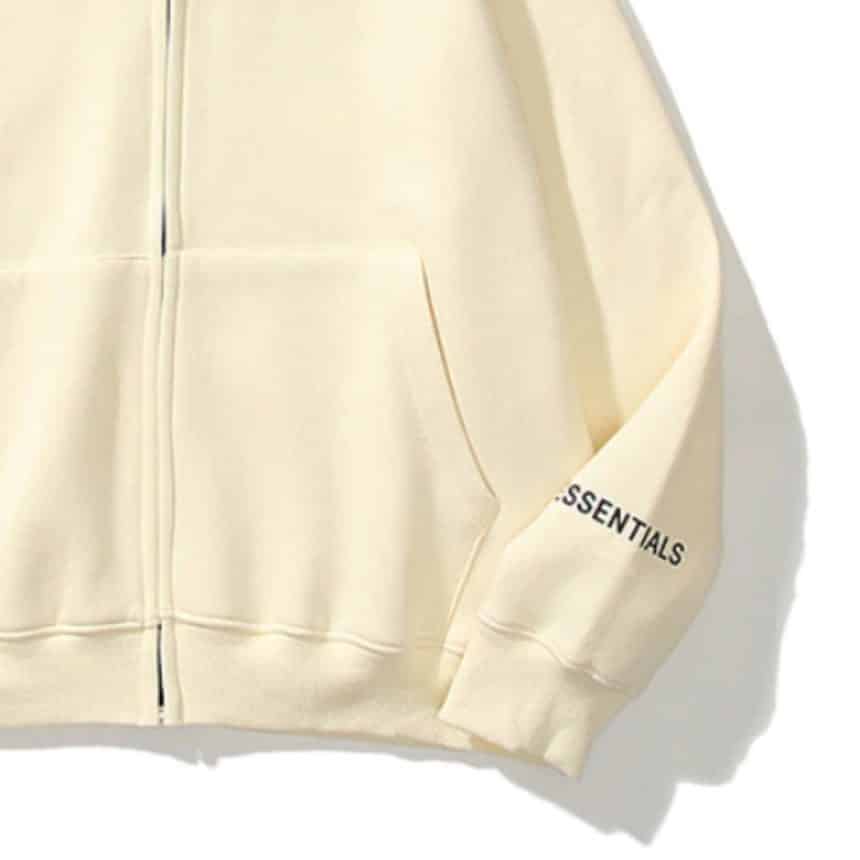 Essentials-Reflective-Print-Zip-up-Cream-Hoodie-1-860x860 Cream zip-up hoodie with ESSENTIALS text on sleeve, showcasing minimalist style and comfy fashion. | Sky Rye Design Cream zip-up hoodie with ESSENTIALS text on sleeve, showcasing minimalist style and comfy fashion.