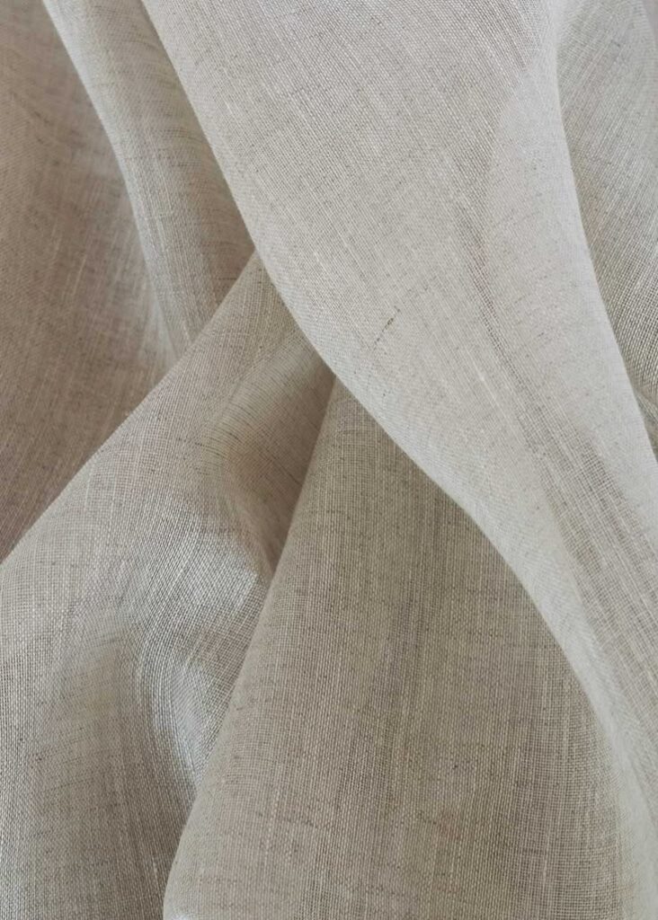 Close-up of textured beige linen fabric, showcasing natural fibers and elegant drape. Ideal for home decor and fashion.