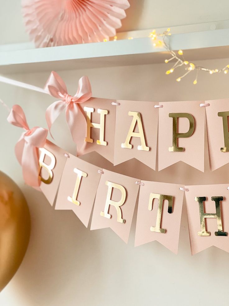 Pink and gold birthday banner with bows and lights creating a festive party decoration.