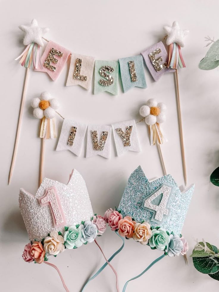 Pastel-themed birthday decorations with name banner and floral crowns for ages one and four.