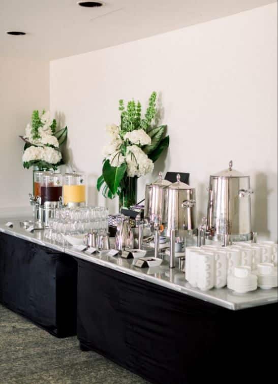 Elegant drink station with coffee urns, juices, and floral arrangements at conference event.