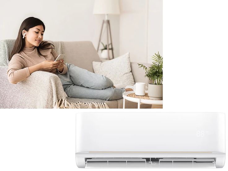 Find Your Flow_ Carriers Comfort Series High Wall Indoor Unit Woman relaxing on couch with smartphone and earbuds, enjoying cool air from modern wall-mounted air conditioner. | Sky Rye Design Woman relaxing on couch with smartphone and earbuds, enjoying cool air from modern wall-mounted air conditioner.