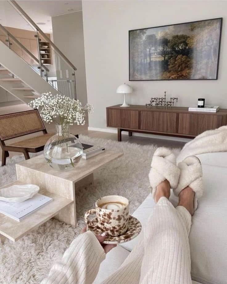 Cozy modern living room with fluffy slippers, coffee, and soft decor, offering a relaxing atmosphere and stylish design.