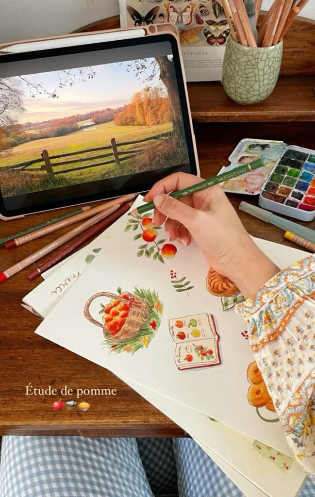Person drawing apples with colored pencils and paints, inspired by a scenic landscape on an iPad screen.