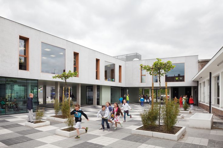 Modern school courtyard with children playing, featuring contemporary architecture and vibrant outdoor spaces.