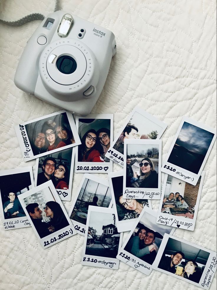 Instant camera with several dated and labeled Polaroid photos on a quilted surface.