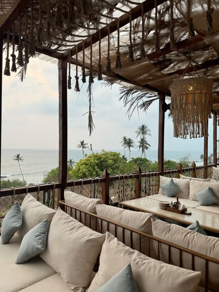 Goa Cozy beachside lounge with white cushions, overlooking ocean and palm trees. Perfect for relaxation and ocean views. | Sky Rye Design Cozy beachside lounge with white cushions, overlooking ocean and palm trees. Perfect for relaxation and ocean views.