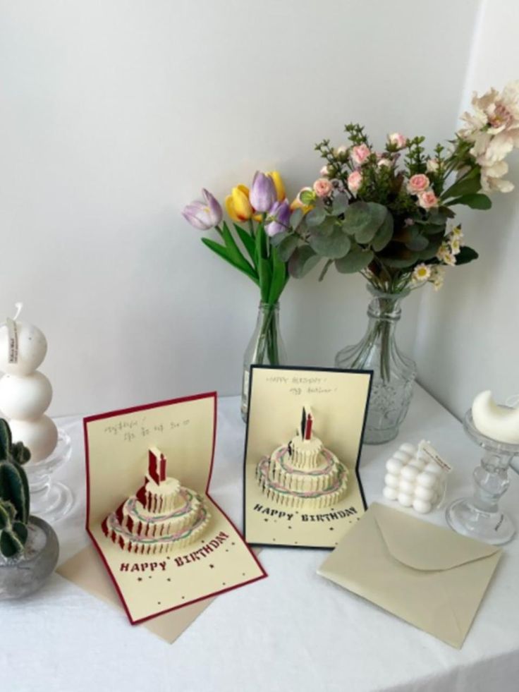 Birthday pop-up cards with flowers and envelopes on a table for decoration.