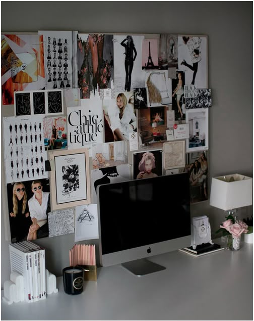 Stylish desk with mood board, computer, books, and decor; creative inspiration in a chic home office setting.