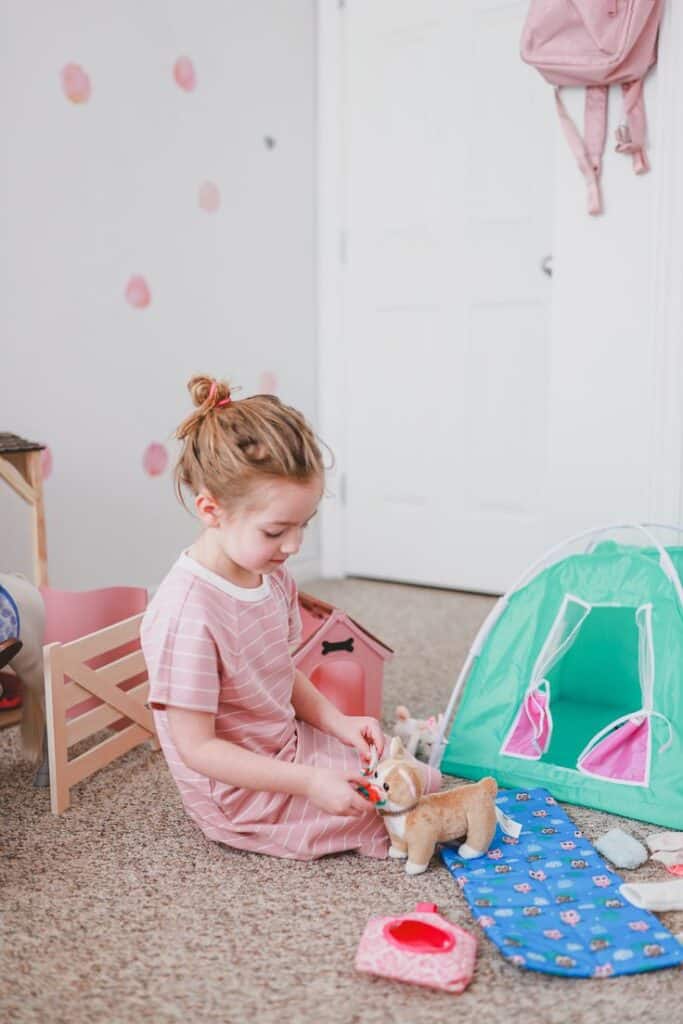 Child playing with toy dog and tent in colorful playroom.