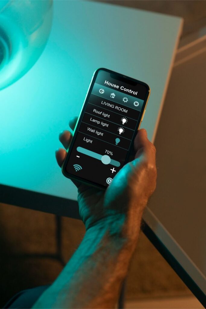 Person using smartphone app for smart home lighting control.