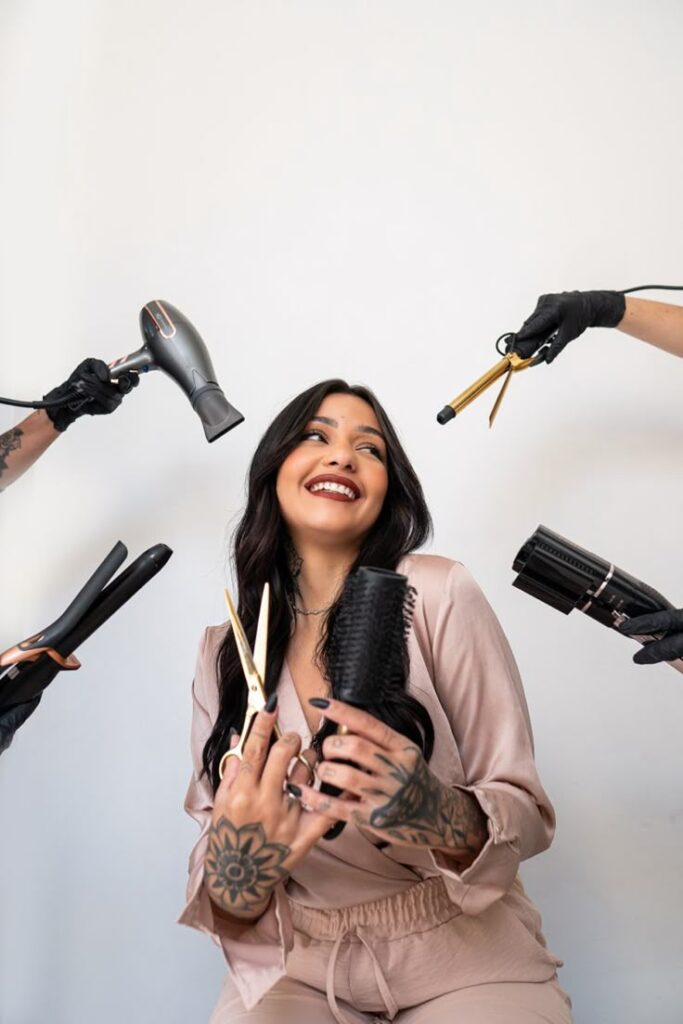 Smiling woman surrounded by hairstyling tools, embracing beauty and hair care.